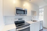 Located at 1772 Church St NW in Washington, DC's vibrant 20036 corridor, this thoughtfully designed one-bedroom, one-bathroom residence offers a clean, modern aesthetic across a single floor. The open layout makes efficient use of space, connecting a bright living room to a well-appointed kitchen equipped with stainless steel appliances, including a range and refrigerator, set against crisp white cabinetry.

The living room is bathed in natural light through large windows that frame views of surrounding greenery, creating an inviting and airy atmosphere. Wood-tone flooring runs throughout, complementing the neutral white walls and adding warmth to the contemporary design. A distinctive frosted glass sliding door adds a stylish architectural touch that enhances the open feel of the main living area.

The bedroom offers a comfortable, private retreat with the same consistent hardwood-style flooring and clean white walls. The full bathroom is finished with large-format light tile flooring, a wood-grain vanity with a white countertop, and a tub-shower combination surrounded by marble-style tile surround, all accented with polished chrome fixtures. The overall ambiance of the residence is bright, minimalist, and move-in ready, ideal for those seeking a modern urban home in Washington, DC.