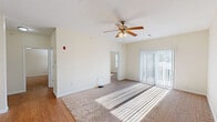 Located at 985 22nd Ave in Silvis, IL, this single-floor residence offers a practical and comfortable layout with 2 bedrooms and 2 bathrooms. The living room serves as the heart of the home, featuring a ceiling fan with light fixture, plush carpeting, and sliding glass doors with vertical blinds that flood the space with natural light and provide outdoor access. Hardwood-style flooring transitions seamlessly into the carpeted areas, adding visual variety to the open layout. The kitchen is well-equipped with warm wood cabinetry, light countertops, black appliances including an electric range and built-in microwave, a double sink, and durable wood-look flooring. A set of double closet doors offers convenient pantry or storage space. Both bedrooms are carpeted and feature ceiling fans with lighting, natural light from windows, and a bright, neutral color palette. The generously sized primary bedroom includes access to a walk-in closet outfitted with wire shelving for ample storage. The bathrooms are finished with tile flooring, wood vanities, mirrored medicine cabinets, and full bathtub and shower combinations. Two dedicated closets throughout the home provide additional storage. The overall ambiance is clean, bright, and move-in ready.