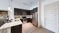 This single-floor residence offers a thoughtfully designed layout with multiple bedrooms, bathrooms, and a well-equipped kitchen. The kitchen is a functional highlight, featuring dark espresso cabinetry extending to the ceiling, light quartz countertops, a gray subway tile backsplash, and a full suite of stainless steel appliances including a French door refrigerator, electric range, and built-in microwave. Track lighting and wood-look flooring complete the space.

The bedrooms are carpeted and receive natural light through large windows dressed with blinds and coordinating curtain panels. Ceiling fans are present in the bedrooms, adding to everyday comfort. The primary bedroom connects to a walk-in closet outfitted with dual hanging rods and shelving, providing generous storage capacity.

The bathrooms feature dark vanity cabinetry paired with white countertops and framed mirrors. Wood-look flooring runs throughout the bathrooms. At least one bathroom includes a full soaking tub with a shower curtain rod, while a secondary bathroom serves as a half or three-quarter bath. Neutral wall tones and clean finishes throughout the residence contribute to a cohesive, contemporary aesthetic.