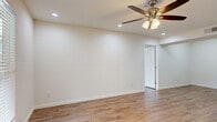 Located at 3200 Mangum Rd in Houston, TX, this single-story 2-bedroom, 3-bathroom home offers a well-designed layout with consistent finishes throughout. Warm hardwood-style flooring runs continuously across the living spaces, complemented by clean white walls and ceiling fans with light fixtures in every room, ensuring comfort and brightness year-round.

The open-concept kitchen features rich wood cabinetry, granite countertops, a stainless steel sink, and black appliances including a range and refrigerator. A pass-through window with a granite-topped bar connects the kitchen to the living area, making it ideal for entertaining.

The living room is spacious and bright, with recessed lighting and easy access to adjoining spaces. Both bedrooms are well-proportioned, each receiving natural light through slatted-blind windows and equipped with ceiling fans. The generously sized primary bedroom includes its own dedicated bathroom.

All three bathrooms carry the same cohesive design language: granite-topped wood vanities, hardwood-style flooring, and clean white walls. One full bath features a tub-shower combination with floor-to-ceiling marble-style tile surround. Closets and hallways further enhance the functional flow of the floor plan, making this home efficient and comfortable throughout.