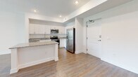 Located at 1414 SW 17th Pl in Cape Coral, Florida, this single-floor residence offers a clean, modern design with a bright and open layout throughout. The kitchen is a standout feature, showcasing crisp white shaker cabinetry, granite countertops, a stainless steel appliance suite including a French door refrigerator, electric range, built-in microwave, and dishwasher, all complemented by wood-look plank flooring that extends seamlessly through the living areas. A peninsula provides additional counter space and connects the kitchen to the open living area, which is bathed in natural light and accented by recessed lighting. The bedrooms feature tray ceilings with ceiling fans, adding an architectural touch and a sense of volume. One bedroom opens directly to a private balcony through sliding glass doors, offering peaceful views of lush tropical palms. A walk-in closet with wire shelving provides generous storage. The bathroom is well-appointed with a frameless-style sliding glass shower enclosure, white tile surround, and granite vanity countertop. Wood-look flooring and white walls throughout lend the space a cohesive, contemporary aesthetic well suited to Florida living.