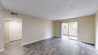 Located at 3351 Cottage Way in Arden-Arcade, California, this single-story, 2-bedroom, 1-bathroom unit offers a well-organized layout with a practical flow throughout. Dark wood-style flooring runs through the main living areas and hallways, complemented by neutral beige walls and textured ceilings that lend a clean, consistent aesthetic.

The living room is a comfortable, open space bathed in natural light, with sliding glass doors that open directly onto a private patio — ideal for indoor-outdoor living. Adjacent to the living room, the combined dining and kitchen area is thoughtfully designed, featuring white shaker-style cabinetry, granite-look countertops, a stainless steel sink, and black appliances including a gas range and full-size refrigerator. A window above the sink brings in additional natural light.

The spacious primary bedroom is carpeted for comfort and includes a ceiling fan, a window for natural light, and access to a generous closet with built-in hanging rods. The second bedroom also features carpeting and its own closet. Three closets in total provide ample storage throughout the unit.

The full bathroom offers a tub/shower combination, wood-style flooring, and a window for ventilation. Additional conveniences include a dedicated laundry area and a utility room. Two hallways connect the spaces efficiently, completing this functional and well-appointed home.