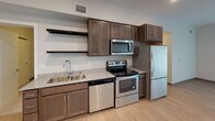 Located at 526 3rd Ave SW in Rochester, MN, this single-floor unit offers a clean, contemporary design with a practical and well-organized layout. The open-concept living and kitchen area is bright and spacious, featuring light hardwood-style flooring, recessed lighting, and a large sliding glass door that allows natural light to fill the room.

The kitchen is well-appointed with dark espresso-toned shaker-style cabinetry, granite-look countertops, and a full suite of stainless steel appliances, including a refrigerator, electric range, built-in microwave, and dishwasher. A hallway connects the main living area to the private rooms beyond.

The bedroom features soft carpeting, a generous window fitted with horizontal blinds, and a closet, creating a calm and comfortable retreat. The bathroom is finished with the same dark cabinetry seen in the kitchen, complemented by a granite-top vanity, tile flooring, a wall-mounted mirror with vanity lighting, and a full shower-tub combination. Additional storage is provided by a closet near the entryway. The overall aesthetic is modern and consistent, with neutral tones carried throughout the space.