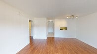 This single-floor unit offers a clean, functional layout with a bright and open feel throughout. The main living area is finished with warm hardwood-style flooring that extends through the common spaces and bedrooms, creating a cohesive and inviting atmosphere. White walls and a textured ceiling complement the natural light that filters in through large windows, lending the space an airy quality.

The kitchen is accessed via an arched entryway and features white raised-panel cabinetry extending to the ceiling for ample storage, white countertops, a stainless steel refrigerator, a stainless steel dishwasher, and an electric range. Light ceramic tile flooring grounds the kitchen, which also benefits from overhead fluorescent lighting.

The bedrooms are well-proportioned, each with hardwood-style flooring and large windows that bring in generous natural light and views of surrounding greenery. The rooms are finished simply with white walls, offering a versatile canvas for personalization.

The bathroom is finished in a clean, all-white palette with ceramic tile flooring, a full tub-shower combination with white tile surround, and white vanity cabinetry. A hallway with tile flooring connects the entry to the main living spaces, completing the unit's straightforward and practical flow.