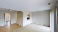 This two-floor residential space offers a clean, functional layout designed for comfortable everyday living. The main living area is finished with soft, neutral-toned walls that lend a calm and airy atmosphere throughout. Underfoot, a combination of smooth hardwood flooring and plush wall-to-wall carpeting defines the different zones of the space, adding both warmth and practicality.

A standout architectural detail is the pass-through window connecting the kitchen to the living area, allowing for an open, communicative flow between the two spaces while maintaining a degree of separation. The kitchen, visible through this opening, is equipped with cabinetry and appliances, offering a compact yet efficient cooking environment.

The living area is generously proportioned, with white ceilings that enhance the sense of height and brightness. Recessed lighting and track lighting provide versatile illumination options, complementing the natural light that filters into the space. Clean white baseboards throughout offer a crisp finishing touch against the muted wall tones.

With its straightforward design, neutral palette, and practical layout spread across two floors, this space provides a solid foundation that is both move-in ready and highly adaptable to a variety of personal styles and needs.