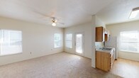 This single-floor residence offers a practical and comfortable layout designed to maximize functionality across its living spaces. The open-concept living area is finished with plush carpeting and features a ceiling fan with light fixture, creating a bright and airy atmosphere. Natural light flows in through multiple windows and a glass-paneled exterior door that leads to a small balcony or patio, seamlessly connecting the interior to the outdoors. Adjacent to the living area, the kitchen is configured in a classic galley style, featuring warm-toned wood cabinetry, laminate countertops, a double-basin sink, and includes appliances such as an electric range, refrigerator, and dishwasher. Light hardwood-style flooring runs throughout the kitchen, adding warmth and easy maintenance. A pendant light fixture provides focused illumination over the workspace. The bedrooms are carpeted and each equipped with a ceiling fan, window with blinds for natural light and privacy, and at least one closet. The two bathrooms share a consistent design, each featuring wood-toned cabinetry, a tub and shower combination, wood-style flooring, and a toilet, maintaining a clean and cohesive aesthetic throughout the unit.