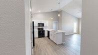 Located at 3276 Jim St in Rapid City, South Dakota, this single-floor, 2-bedroom, 2-bathroom residence offers a clean, contemporary design with thoughtful finishes throughout. The open-concept kitchen and living area serves as the heart of the home, showcasing vaulted ceilings that lend an airy sense of volume. The kitchen is well-appointed with white shaker cabinetry, a generous peninsula counter featuring light stone-look surfaces and an integrated sink, black appliances including a refrigerator and range, pendant lighting, and recessed ceiling lights. Durable wood-look vinyl plank flooring runs through the main living and kitchen areas, while plush neutral carpet is found in the bedrooms. The living room features a window and exterior door that invite natural light and outdoor views. The primary bedroom is a comfortable retreat, carpeted and brightened by a window with outdoor views. Both bathrooms are finished with wood-look vinyl floors, white cabinetry with stone-look countertops, and full tub-shower combinations with chrome fixtures. A dedicated closet with built-in hanging rod offers practical storage. Neutral gray wall tones and white trim create a cohesive, modern palette throughout this well-designed Rapid City residence.
