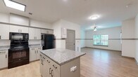 Located at 2401 6th St in Lake Charles, Louisiana, this single-story, one-bedroom, one-bathroom unit offers a well-designed layout across a comfortable footprint. The interior features light wood-look flooring throughout, crisp white walls with a subtle gray chair rail accent, and ceiling fans in the main living areas. The open kitchen is a standout, equipped with white shaker-style cabinetry, granite countertops, a center island with bar seating, and black appliances including a refrigerator, range, and over-the-range microwave. The kitchen flows seamlessly into the living room, which receives natural light through window blinds and offers a relaxed, open ambiance. The bedroom is a well-proportioned retreat with a ceiling fan, a window overlooking greenery, and access to multiple closets for generous storage. The bathroom features marble-style tile flooring, wall-mounted grab bars, and a medicine cabinet, reflecting a clean and functional design. Additional conveniences include a dedicated laundry area, a pantry, and a private patio. The unit's consistent neutral palette and modern finishes create a bright, cohesive living environment throughout.