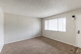 This single-floor unit offers a practical and well-organized layout, thoughtfully designed for comfortable everyday living. The living area is finished with warm beige carpet and bright white walls, creating a clean, neutral canvas throughout. A textured popcorn ceiling adds a classic touch, while the open sightline to the kitchen enhances the sense of space.

The kitchen is efficiently arranged in a galley-style configuration, featuring crisp white shaker cabinetry with matte black hardware, dark speckled countertops, and wood-look plank flooring. It is equipped with a gas range, black refrigerator, dishwasher, and a double-basin sink, providing all the essentials for daily use.

The bedroom is generously proportioned with plush carpeting and a window fitted with vertical blinds that allow for adjustable natural light. A closet with overhead shelving provides convenient storage directly adjacent to the room.

The bathroom continues the cohesive design aesthetic, featuring the same white cabinetry and dark countertop as the kitchen, paired with a single-basin vanity, a large mirror, and a tub-shower combination. Wood-look flooring ties the wet areas of the unit together seamlessly. Overall, the space presents a consistent, updated aesthetic with a clean and functional design throughout.