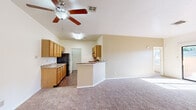 This single-story, 2-bedroom, 2-bathroom home offers a practical and comfortable layout across a thoughtfully designed floor plan. The open-concept kitchen and living area serves as the heart of the home, featuring vaulted ceilings that enhance the sense of space. The kitchen is equipped with warm honey-toned wood cabinetry, granite-style countertops, a black refrigerator, and a peninsula that provides additional workspace and casual dining options. Hardwood-style flooring runs throughout the kitchen, while plush carpeting extends into the living area. A ceiling fan overhead adds both comfort and style to the shared space. A sliding glass door in the living area fills the room with natural light and provides direct access to the outdoors. Both bedrooms are carpeted and feature ceiling fans and windows with outdoor views. The spacious primary bedroom includes direct access to a dedicated bathroom and a generous walk-in closet with built-in hanging rods. The bathrooms feature tile-surround tub/shower combos, wood-style flooring, and vanities with granite-style countertops. Additional highlights include a pantry, hallway, and two closets, ensuring ample storage throughout the home.