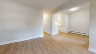 Located at 1791 King St E in Hamilton, Ontario, this thoughtfully updated 2-bedroom, 1-bathroom unit offers a clean, modern aesthetic throughout its single-floor layout. Light-toned laminate flooring flows seamlessly across all living areas, complemented by neutral wall tones and crisp white trim, creating a bright and cohesive atmosphere.

The open-concept living and dining area is generously proportioned, with large black-framed windows that invite abundant natural light and leafy outdoor views. The kitchen features white cabinetry, ample upper and lower storage, and a functional pass-through design that connects well to the living space.

The spacious primary bedroom offers a large window with green tree views and baseboard heating, while the second bedroom is well-sized with its own window and direct access to a closet. Three closets are distributed throughout the unit, providing excellent storage. The bathroom is finished with classic white subway tile surrounding a full soaker tub with chrome fixtures.

A private balcony with sleek glass-panel railings overlooks a mature tree canopy, offering a peaceful outdoor retreat. The unit also includes a dedicated laundry area and a welcoming entrance, rounding out a practical and comfortable living space.