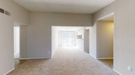 This well-appointed single-floor residence offers a thoughtfully designed layout that balances comfort and functionality throughout. The living room serves as a standout centerpiece, featuring soaring vaulted ceilings that amplify the sense of space, along with a classic white brick fireplace flanked by two windows fitted with plantation-style shutters, creating a warm and inviting focal point. The open-concept layout connects the living area to a dining space and beyond to a bright area with sliding glass doors that welcome generous natural light. The galley-style kitchen is efficiently designed with ample white cabinetry, light quartz-style countertops, a subway tile backsplash, herringbone-pattern luxury vinyl flooring, and stainless steel appliances including a refrigerator, electric range, and dishwasher. The bedrooms are carpeted and comfortable, each equipped with ceiling fans and window blinds that allow for controlled natural light. The primary bathroom features a vanity with a soaking tub, a separate walk-in shower with glass enclosure, and elegant herringbone-patterned flooring. A secondary bathroom includes a tiled tub-shower combination. Neutral tones and clean finishes throughout give the space a move-in-ready, versatile appeal.