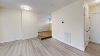 Located at 26 Beacon St in Burlington, MA, this efficiently designed single-floor unit offers a well-organized layout encompassing a living room, kitchen, two bathrooms, and a closet. The interior is finished with light gray wood-look flooring throughout, cream-toned walls, and clean white trim, creating a bright and cohesive aesthetic.

The open living area is airy and functional, benefiting from natural light streaming through large windows that overlook the exterior. A structural column subtly defines the transition between the living space and the kitchen without interrupting the open feel.

The kitchen is well-appointed with white cabinetry, granite-style countertops, and a full suite of stainless steel appliances, including a refrigerator, range, and dishwasher. A closet door adjacent to the kitchen provides convenient storage access.

Two bathrooms serve the unit, each finished with granite-style vanity countertops, white cabinetry, and tile flooring. One bathroom includes a full tub-shower combination with a large mirror above the vanity, while the second is a compact water closet-style space.

The unit's neutral palette and consistent finishes throughout lend it a clean, move-in-ready appearance. Its location in Burlington, MA, provides convenient access to local amenities, dining, and major commuter routes.