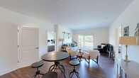 This thoughtfully designed 2-bedroom, 4-bathroom single-floor residence offers a functional and stylish open-concept layout. The kitchen is a standout feature, outfitted with rich dark cabinetry, stainless steel appliances, and striking granite countertops that extend across a peninsula with bar seating and pendant lighting overhead. The kitchen flows seamlessly into a combined dining and living area, where dark hardwood flooring, generous natural light, and large sliding glass doors leading to a balcony create an inviting, connected atmosphere with views of lush greenery.

A secondary living area provides additional lounge space and features a sleek fireplace with a dark stone surround, complemented by continued hardwood flooring. The primary bedroom is a comfortable retreat with plush carpeting, a ceiling fan, and a window overlooking natural surroundings. The primary bathroom impresses with an expansive granite double vanity and a tiled walk-in shower. The second bedroom, also carpeted, offers a quiet and cozy setting.

Four full bathrooms ensure convenience throughout. The dedicated laundry room includes a full-size washer and dryer alongside dark wood cabinetry for additional storage. A closet and multiple well-placed bathrooms round out this efficiently organized and elegantly finished residence.