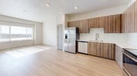 Located in Pleasant Grove, Utah, this multi-story home spans three floors and offers a well-organized layout with two bedrooms, two bathrooms, and a range of functional support spaces. The lowest level houses a utility room with mechanical systems and provides the structural foundation of the home. The ground floor includes an attached garage with an automatic opener and electrical panel, plus a welcoming entrance area complete with a built-in coat rack and storage bench, bathed in natural light from a staircase window. The main living floor features a bright, open-plan dining, kitchen, and living area finished with light hardwood-style flooring and recessed lighting. The kitchen is outfitted with wood-toned cabinetry, stainless steel appliances including a refrigerator, range, microwave, and dishwasher, and light countertops. The uppermost floor is the largest and hosts both bedrooms, two bathrooms, closets, and a hallway. The primary bedroom is generously sized with plush carpet and recessed lighting, accompanied by a dedicated closet and a well-appointed en-suite bathroom featuring a wide vanity with a quartz countertop, wood-toned cabinetry, a large mirror, and a tub-shower combination. The secondary bedroom is bright and carpeted with a large window. Throughout, the home maintains a clean, modern aesthetic with neutral tones and quality finishes.