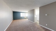 Located at 1321 Centennial Dr in Farmington, MN, this two-bedroom, one-bathroom residence offers a practical and well-organized single-floor layout. The open-concept living and dining area is generously sized, featuring warm neutral-toned carpet, a textured ceiling, and a bold teal accent wall that adds a pop of color. Natural light filters in through a large window with blinds, creating a bright and welcoming atmosphere. Baseboard heating units are present throughout the unit.

The kitchen is efficiently designed with white cabinetry, granite-style countertops, a white electric range, and a full-size refrigerator, all set on durable wood-look vinyl flooring that contrasts nicely with the carpeted living areas.

Both bedrooms are carpeted and painted in soft, neutral tones. The spacious primary bedroom features a wide window for natural light and a baseboard heater, while the second bedroom is equally comfortable and includes a double bi-fold closet for ample storage. Additional closets throughout the unit provide further organizational convenience.

The bathroom is finished with small-tile mosaic flooring, a full tub-shower combo with a clean white surround, and a granite-style vanity countertop, rounding out this functional and tidy living space.
