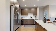 Located at 5851 Columbia Pike in Falls Church, VA, this well-appointed 2-bedroom, 2-bathroom residence offers a thoughtfully designed single-floor layout with a seamless flow between living spaces. The open-concept kitchen and living area serves as the heart of the home, featuring rich dark-toned cabinetry, crisp white quartz countertops, stainless steel appliances, a subway tile backsplash, and a central island with bar seating — ideal for both meal prep and casual dining. Light wood-tone flooring runs throughout, complementing the clean, modern aesthetic. The living room offers generous space bathed in natural light from large windows, with direct access to a private balcony. The primary bedroom is a comfortable retreat with its own walk-in closet and an en-suite bathroom finished in neutral tile, featuring a walk-in shower and sleek cabinetry. The second bedroom is distinguished by a bold teal accent wall and a bright window with outdoor views, bringing in natural light. A second full bathroom and dedicated laundry areas add everyday convenience. Two closets and a well-organized entry complete the layout. Recessed lighting throughout enhances the modern ambiance of this thoughtfully crafted residence.