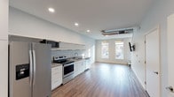 Located at Weston Street SE in Grand Rapids, Michigan, this two-floor space offers a thoughtfully designed interior with modern finishes throughout. The open kitchen is a standout feature, showcasing stainless steel appliances including a French door refrigerator, electric range, and dishwasher, complemented by granite countertops, white cabinetry, open shelving, and durable wood-look flooring. A wall-mounted TV bracket and exposed ductwork detail add a contemporary, urban character to the main living area, which is brightened by street-facing windows that invite natural light. The upper floor is accessible via a staircase visible in the layout and features carpeted bedrooms finished in soft, neutral gray tones. The rooms are well-proportioned and receive ample natural light through large windows with views of the surrounding neighborhood. The bathroom is cleanly appointed with granite-topped white vanity cabinetry, a undermount sink, and wood-look flooring, maintaining the consistent modern aesthetic found throughout the space. A second bathroom area continues the same refined, minimalist design. The overall ambiance is clean, bright, and move-in ready, reflecting a contemporary residential aesthetic well-suited to urban living in the heart of Grand Rapids.