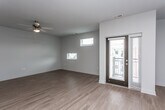 This single-floor unit offers a clean, modern design highlighted by warm hardwood-style flooring that flows consistently throughout the entire space. The open-concept layout seamlessly connects the living area to the kitchen, creating a spacious and functional environment.

The living area is bright and airy, featuring a ceiling fan with a light fixture, multiple windows that allow natural light to fill the room, and a glass-paneled exterior door providing direct access to an outdoor balcony or patio area.

The kitchen is well-appointed with dark espresso cabinetry, granite countertops, a tile backsplash, and a full suite of stainless steel appliances including a refrigerator, electric range, built-in microwave, and dishwasher. A double-basin undermount sink with a contemporary faucet is set into the kitchen island or peninsula, which also serves as a natural divider between the kitchen and living spaces. Pendant lighting adds a stylish touch overhead.

The bathroom is neatly finished with a dark vanity cabinet topped with granite countertops, a dual-mirror setup, hardwood-style flooring, and a soaking tub with a shower curtain rod. A separate interior door from the bathroom provides additional connectivity within the unit.

Overall, the space presents a cohesive, contemporary aesthetic with consistent finishes and a practical, open floor plan.