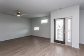 This single-floor unit offers a clean, modern design highlighted by warm hardwood-style flooring that flows consistently throughout the entire space. The open-concept layout seamlessly connects the living area to the kitchen, creating a spacious and functional environment.

The living area is bright and airy, featuring a ceiling fan with a light fixture, multiple windows that allow natural light to fill the room, and a glass-paneled exterior door providing direct access to an outdoor balcony or patio area.

The kitchen is well-appointed with dark espresso cabinetry, granite countertops, a tile backsplash, and a full suite of stainless steel appliances including a refrigerator, electric range, built-in microwave, and dishwasher. A double-basin undermount sink with a contemporary faucet is set into the kitchen island or peninsula, which also serves as a natural divider between the kitchen and living spaces. Pendant lighting adds a stylish touch overhead.

The bathroom is neatly finished with a dark vanity cabinet topped with granite countertops, a dual-mirror setup, hardwood-style flooring, and a soaking tub with a shower curtain rod. A separate interior door from the bathroom provides additional connectivity within the unit.

Overall, the space presents a cohesive, contemporary aesthetic with consistent finishes and a practical, open floor plan.