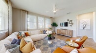 This single-story residence on Harper Blvd in Davenport, Florida, presents a thoughtfully designed layout with contemporary finishes throughout. Entry is welcomed by a stylish foyer featuring wood-look flooring, neutral walls, and an elegant console table beneath a framed mirror—setting a polished tone for the rest of the home.

The open-concept living area is bright and inviting, with multiple windows allowing generous natural light to fill the space. A ceiling fan overhead and wood-look flooring underfoot contribute to the comfortable, casual ambiance. The kitchen is a standout feature, showcasing white cabinetry, gray quartz countertops, a tile backsplash, stainless steel appliances, and a curved breakfast bar with seating—ideal for both everyday use and entertaining.

The bedrooms offer restful retreats, each with large windows, wood-look flooring, and ceiling fans. One bedroom features a bold teal accent wall, while another offers a serene, light-filled atmosphere. A walk-in closet with wire shelving provides generous storage. The bathroom is finished with white shaker cabinetry, black hardware, a glass-enclosed shower, and coordinating flooring. A dedicated laundry area with a full-size washer and dryer completes this well-rounded home.