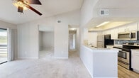 Located at 3000 Foxhill Cir in Apopka, FL, this single-story 1-bedroom, 2-bathroom home offers a thoughtfully designed layout with comfortable living spaces throughout. The living room makes a strong first impression with its vaulted ceilings, ceiling fan, soft carpeting, and a tile-surround fireplace that serves as a focal point. Natural light filters in through blinds-covered windows offering pleasant outdoor views of the surrounding landscape. The kitchen is well-appointed with white shaker-style cabinetry, a decorative tile backsplash, stainless steel appliances including a refrigerator, electric range, and microwave, plus a raised tray ceiling and wood-look flooring. A breakfast bar provides a convenient transition between the kitchen and living area. The spacious bedroom features plush carpeting, a ceiling fan, a large window with scenic views, and generous closet space including both a walk-in closet and an additional built-in closet. Two full bathrooms are included, each with clean, neutral finishes — one featuring a framed vanity mirror, granite-style countertops, and white cabinetry, the other with a tiled tub surround. A dedicated laundry area and hallway complete this efficiently organized home.