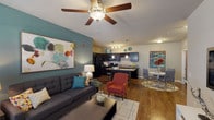 This well-appointed 2-bedroom, 2-bathroom unit delivers a comfortable and functional single-floor layout with a contemporary aesthetic. The open-concept living area serves as the heart of the home, featuring rich hardwood-style flooring, a teal accent wall, and a ceiling fan that enhances the bright, airy ambiance. Large windows in the living room invite natural light and provide a welcoming atmosphere.

The kitchen is a standout feature, equipped with dark espresso cabinetry, granite-style countertops, black appliances including a refrigerator, range, and microwave, and a central island with bar seating — ideal for both cooking and casual dining. A dedicated dining area sits adjacent to the kitchen, completing the seamless open flow.

Both bedrooms are comfortably sized, each with plush carpeting, ceiling fans, and ample closet space. The primary bedroom features a teal accent wall, adding a bold design touch. The primary bathroom includes a dual-sink vanity with dark cabinetry, granite countertops, hardwood-style flooring, and a full tub-shower combination. The second bathroom is equally well-finished, with a tub-shower, dark vanity, and matching flooring.

Throughout the unit, the consistent use of dark cabinetry, warm flooring, and carefully chosen accent colors creates a cohesive and modern living environment.