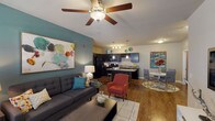 This well-appointed 2-bedroom, 2-bathroom unit delivers a comfortable and functional single-floor layout with a contemporary aesthetic. The open-concept living area serves as the heart of the home, featuring rich hardwood-style flooring, a teal accent wall, and a ceiling fan that enhances the bright, airy ambiance. Large windows in the living room invite natural light and provide a welcoming atmosphere.

The kitchen is a standout feature, equipped with dark espresso cabinetry, granite-style countertops, black appliances including a refrigerator, range, and microwave, and a central island with bar seating — ideal for both cooking and casual dining. A dedicated dining area sits adjacent to the kitchen, completing the seamless open flow.

Both bedrooms are comfortably sized, each with plush carpeting, ceiling fans, and ample closet space. The primary bedroom features a teal accent wall, adding a bold design touch. The primary bathroom includes a dual-sink vanity with dark cabinetry, granite countertops, hardwood-style flooring, and a full tub-shower combination. The second bathroom is equally well-finished, with a tub-shower, dark vanity, and matching flooring.

Throughout the unit, the consistent use of dark cabinetry, warm flooring, and carefully chosen accent colors creates a cohesive and modern living environment.
