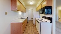 This single-floor apartment in Ann Arbor, Michigan offers a practical and straightforward layout designed for comfortable everyday living. The living area is finished with neutral-toned carpet and features multiple windows that allow natural light to filter in, creating a bright and open atmosphere. A ceiling fan adds functionality to the space, while the neutral wall colors provide a versatile backdrop throughout.

The bedroom is a well-proportioned, carpeted room with a window overlooking the outdoors, offering views of the surrounding greenery. Its clean, simple design provides ample space for furnishings and personal customization.

The galley-style kitchen is efficiently organized, featuring warm oak cabinetry on both sides, light-toned countertops with a stainless steel sink, and wood-look flooring. It is equipped with a white electric range, refrigerator, dishwasher, and an over-the-range microwave, providing all essential appliances. A door at the end of the kitchen leads to additional storage or utility access.

The full bathroom includes tile flooring in earthy tones, a vanity with wooden cabinetry and a light countertop, and a full tub-shower combination with neutral stone-look tile surround and a curved curtain rod. The overall ambiance of the apartment is clean, functional, and move-in ready.