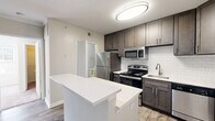 Located in Alexandria, VA, this well-appointed one-bedroom, one-bathroom residence offers a thoughtfully designed layout across a single floor. The open-concept kitchen and living area serves as the heart of the home, featuring dark espresso cabinetry, white quartz countertops, a classic subway tile backsplash, and a full suite of stainless steel appliances including a refrigerator, electric range, and over-the-range microwave. A peninsula island provides additional counter space and casual seating. Wood-look flooring runs throughout the main living area, adding warmth and durability. The bedroom is carpeted for comfort, benefits from generous natural light through large windows with blinds, and includes a ceiling fan for year-round climate control. Two closets provide ample storage throughout the unit. The bathroom features a full tub-shower combination with clean white tile surround, a vanity with dark cabinetry, and wood-look flooring. A dedicated in-unit laundry area adds everyday convenience, while a private balcony offers a pleasant outdoor retreat. The space is surrounded by mature trees, providing a serene natural backdrop.