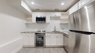 Located at 2617 Crocker St in Houston's vibrant Montrose neighborhood, this efficiently designed single-floor unit makes smart use of its compact footprint. The space is unified by light wood-look flooring throughout, crisp white walls, and recessed lighting that keeps the interior feeling bright and clean.

The kitchen is a standout feature, outfitted with white shaker-style cabinetry, open shelving, and a classic white subway tile backsplash. Granite countertops with subtle gray veining provide a polished work surface, while stainless steel appliances — including a range, over-the-range microwave, and refrigerator — deliver a modern, functional aesthetic. A stainless steel sink with a contemporary faucet completes the well-appointed cooking area.

The living room is an open, airy space bathed in natural light from a row of windows along one wall. Clean white walls and light flooring create a neutral canvas, and a visible electrical panel is neatly integrated into the wall.

The entry features a set of dark stone steps leading up to a white paneled door, offering a clean and defined threshold into the unit. The bathroom is finished with classic white hexagonal floor tile and full subway tile walls in the walk-in shower, accompanied by antique brass fixtures that add a refined touch. A dedicated closet completes the layout, providing practical storage within the space.