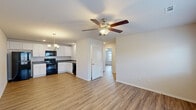 Located at 111 NW 63rd Ave in Highfill, Arkansas, this single-story 2-bedroom, 2-bathroom home offers a clean, modern aesthetic with consistent wood-look flooring and a neutral color palette throughout. The open-concept living room and kitchen area forms the heart of the home, with the living room featuring a ceiling fan, large windows with blinds that invite natural light, and a glass door leading to the exterior. The kitchen is well-equipped with white shaker-style cabinetry, dark countertops, a stainless steel sink, and black appliances including a refrigerator, range, microwave, and dishwasher, all illuminated by recessed lighting and a decorative chandelier. Both bedrooms are comfortably sized, each featuring a ceiling fan, natural light from window, and a built-in closet with shelving and hanging rods. The primary bedroom offers a generous footprint with ample closet space. The two bathrooms are finished with white cabinetry, dark countertops, and wood-look flooring. One bathroom includes a full tub-shower combination, while the other features a more compact layout. The overall ambiance of the home is bright, clean, and move-in ready, reflecting a practical yet attractive design well-suited for comfortable everyday living.