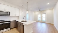 This 1-bedroom, 1-bathroom residence in Georgetown, TX offers a thoughtfully designed open-concept layout with modern finishes throughout. Light wood-style flooring runs continuously across the entire space, creating a cohesive and airy feel.

The kitchen is a standout feature, showcasing a large center island with a white quartz countertop, undermount sink, and stylish globe pendant lighting. Two-tone cabinetry pairs white upper cabinets with warm taupe lower cabinets, complemented by a classic tile backsplash and a full suite of stainless steel appliances, including a refrigerator, range, and over-the-range microwave.

The living area flows directly from the kitchen and is brightened by natural light streaming through a set of French doors that open to a private balcony. A ceiling fan adds comfort and function to the space.

The bedroom is a comfortable retreat with a large window offering outdoor views, a ceiling fan, and access to a well-organized walk-in closet fitted with wire shelving and hanging rods.

The bathroom features a white vanity with quartz countertops and wood-style flooring, maintaining the clean, consistent aesthetic found throughout the home. Neutral tones and recessed lighting complete the polished, move-in-ready presentation of this Georgetown residence.
