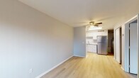 Located on Firwood Drive in Dayton, Ohio, this single-floor unit offers a clean, updated living environment with a cohesive neutral color palette and light hardwood-style flooring that flows seamlessly throughout every room. The open living area is spacious and bright, with soft gray walls, white baseboards, and a ceiling fan with integrated lighting that enhances the airy feel of the space. The kitchen is a standout feature, outfitted with crisp white shaker-style cabinetry, a white subway tile backsplash, granite-look countertops, a stainless steel refrigerator, and a single-basin sink. A skylight above the kitchen brings in additional natural light, adding warmth to the functional workspace. The bedroom is generously sized, featuring the same light hardwood flooring, a ceiling fan, a window for natural light, a wall-unit air conditioner, and a large closet providing ample storage. The bathroom is neatly appointed with a white vanity, a framed mirror, a modern light fixture, and consistent hardwood-style flooring that ties the space together. Throughout the unit, the design is practical and well-maintained, offering a welcoming and move-in-ready environment.