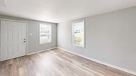 Located at 1603 Roane St in Richmond, Virginia, this two-story, 2-bedroom, 1-bathroom home offers a practical and efficiently designed layout spread across two floors. The main level features a bright, open living area finished with light-toned luxury vinyl plank flooring that gives the space a clean, modern feel. The kitchen is visible from the living area and includes a full-size refrigerator, with access to the exterior via a dedicated entry door. Soft, neutral gray walls on both floors create a cohesive and calming ambiance throughout.

Upstairs, the two bedrooms are finished with rich, warm hardwood floors that add character and charm. The upper level features vaulted ceilings that lend a sense of openness, and multiple windows in each bedroom invite abundant natural light while offering views of the surrounding neighborhood. The bedrooms connect through a hallway that also provides access to the full bathroom, which is equipped with a tub-shower combination.

The home's consistent use of soft gray paint, white trim, and panel-style doors ties the two floors together visually, creating a harmonious design from top to bottom. This well-maintained home in Richmond's 23222 zip code presents a straightforward, functional living environment suited for those seeking a comfortable two-story residence.