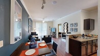 This thoughtfully laid-out one-bedroom, one-bathroom unit offers a comfortable and functional living experience across a single floor. The open-concept living and dining area serves as the heart of the unit, featuring rich hardwood flooring, crown molding, and a bold teal accent wall that adds a striking visual element. A ceiling fan with light fixture keeps the space comfortable, while large sliding glass doors flood the room with natural light and open to an outdoor balcony with views of the surrounding amenities.

The kitchen is well-appointed with dark espresso cabinetry, granite-style countertops, black appliances including a refrigerator, range, and built-in microwave, and track lighting overhead. A peninsula counter with bar seating connects the kitchen to the dining and living areas for a seamless flow.

The bedroom offers a cozy retreat with its own teal accent wall, a ceiling fan, hardwood floors, and windows that invite natural light. A dedicated closet provides storage, and the adjoining bathroom features dark cabinetry, granite countertops, a large vanity mirror, and Hollywood-style lighting.

Completing the unit is a dedicated in-unit laundry room with a full-size washer and dryer, adding exceptional convenience to everyday living.