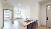 Located at 3812 W Montague Ave in North Charleston, SC, this efficiently designed one-bedroom, one-bathroom residence offers a thoughtfully planned single-level layout. The open-concept kitchen and living area serves as the heart of the home, showcasing a striking two-tone design with navy blue lower cabinets, crisp white upper cabinets, and a geometric hexagon tile backsplash. A center island with granite countertops and an undermount sink anchors the space, complemented by stainless steel appliances including a gas range, microwave, and refrigerator. Light wood-tone flooring flows seamlessly throughout, enhancing the bright, clean aesthetic. The living area receives generous natural light through a large window and is equipped with a ceiling fan. The bedroom is a cozy, well-lit space featuring its own large window with outdoor views and a ceiling fan for year-round comfort. The bathroom is finished with granite countertops on the navy vanity, matte black fixtures, and a full tub-shower combination with built-in shelving. Recessed lighting and panel-style interior doors add polished, modern touches throughout this well-appointed residence.