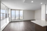 Located on the 17th floor at 35 Brock Street in Hamilton, Ontario, this unit offers a clean, modern aesthetic defined by light hardwood flooring, neutral wall tones, and an abundance of natural light. The layout is thoughtfully organized, with a welcoming entry hallway leading into the main living areas.

The living space is a standout feature, anchored by expansive floor-to-ceiling windows and a sliding glass door that opens to a balcony. The elevated position provides sweeping views of the surrounding waterfront and cityscape, filling the room with bright, open light throughout the day.

The kitchen is well-appointed with a galley-style design, featuring two-tone cabinetry — tall gloss-white upper cabinets paired with taupe lower cabinets — and light quartz countertops. Stainless steel appliances, including a built-in microwave, electric range, and refrigerator, are seamlessly integrated. A subway tile backsplash and recessed lighting complete the polished look.

The bedrooms are generously sized, each featuring large windows with open views and built-in closets with hanging rails. The unit maintains a consistent, contemporary finish throughout, creating a cohesive and functional living environment.