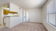 This efficiently designed 1-bedroom, 1-bathroom unit offers a practical and functional layout across a single floor. The combined living and dining area is carpeted in neutral tones, creating a cohesive and comfortable atmosphere. A pass-through counter with an overhead cabinet connects this open area to the kitchen, providing both visual openness and casual dining convenience. The galley-style kitchen is a standout feature, lined on both sides with warm wood-toned cabinetry, ample counter space, and white appliances including a refrigerator, electric range, and dishwasher. Light hardwood-style flooring runs the length of the kitchen, contrasting nicely with the carpeted living areas. The bedroom offers a comfortable footprint, featuring plush carpet, a ceiling fan, and a window dressed with blinds that allows for natural light. A dedicated closet provides storage, while an additional hallway closet adds further functionality. The bathroom is clean and straightforward, equipped with a full soaking tub and shower surround clad in classic white tile, complemented by wood-toned overhead cabinetry. Textured ceilings are consistent throughout the unit, adding a traditional finish to this well-organized and practical living space.