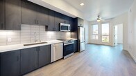 Located at 4555 30th Street in San Diego's vibrant Normal Heights neighborhood, this efficiently designed one-bedroom, one-bathroom unit offers a thoughtfully planned layout across a single floor. Light-toned luxury vinyl plank flooring runs throughout the space, creating a cohesive and clean aesthetic.

The open kitchen is a standout feature, showcasing dark cabinetry that extends floor to ceiling, white subway tile backsplash, light quartz countertops, and a full suite of stainless steel appliances including a refrigerator, range, microwave, and dishwasher. The kitchen flows seamlessly into the living area, which benefits from recessed lighting and a ceiling fan.

The bedroom offers a bright, minimalist retreat with a large window framing views of the surrounding San Diego skyline and palm trees, allowing abundant natural light to fill the room. A stylish sliding barn door adds a modern design touch to the space.

The bathroom is finished in an all-white palette, featuring a tub-shower combination with white tile surround, brushed nickel fixtures, and built-in wall shelving for added storage. The closet provides practical organization with hanging rods and shelving. A hallway connects the rooms cleanly, completing this well-appointed and contemporary urban residence.