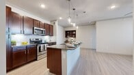 This thoughtfully designed 2-bedroom, 2-bathroom residence offers a comfortable and functional single-floor layout. The open-concept kitchen and living area serves as the heart of the home, showcasing rich dark-wood cabinetry, stainless steel appliances, a subway tile backsplash, and a large granite-topped island with pendant lighting overhead — ideal for both meal prep and casual dining. Light wood-style flooring flows throughout the main living areas, enhancing the bright, airy atmosphere.

The spacious living room benefits from large windows and a ceiling fan, creating a welcoming, well-lit environment. Both bedrooms are generously sized, featuring plush carpet, ceiling fans, and large windows that invite ample natural light and outdoor views. The primary bedroom offers a comfortable retreat, while the second bedroom provides flexible space for guests or a home office.

Each bathroom is finished with granite countertops, dark-wood vanities, and tile flooring. The primary bath includes a walk-in shower, while the second bath features a full soaking tub. A dedicated in-unit laundry room and two closets add practical convenience. Crown molding and consistent finishes throughout lend a polished, cohesive feel to the entire residence.