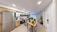 Located at Skyway in Calgary's southwest, this 2-bedroom, 2-bathroom unit offers a thoughtfully planned open-concept layout finished with light hardwood-style flooring, recessed lighting, and a clean, contemporary palette throughout. The combined kitchen and living area forms the heart of the home, where a fully equipped kitchen showcases two-tone cabinetry — warm wood lowers paired with crisp white uppers — complemented by open shelving, a subway tile backsplash, stainless steel appliances, and a white quartz countertop. A dining area flows naturally from the kitchen toward the bright living room, which features a wall-mounted mini-split system for year-round comfort and access to natural light through a large window. The primary bedroom offers a serene retreat with its own walk-in closet, while the second bedroom provides a versatile space suitable for various configurations. Both bathrooms are finished with modern wood-tone vanities and light countertops; one features a glass-enclosed walk-in shower with marble-style tile. The consistent use of light tones, clean lines, and quality finishes gives the entire unit a cohesive and contemporary feel.