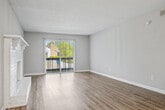 This one-bedroom, one-bathroom unit is thoughtfully designed to maximize its well-proportioned floor plan. The living room serves as the centerpiece of the space, featuring a striking white brick fireplace with a built-in mantle and hearth that adds a classic architectural element. Wood-style plank flooring runs throughout the main living areas, complementing the neutral gray tones of the walls. A sliding glass door with vertical blinds opens to a private balcony, allowing natural light to fill the room.

The kitchen is equipped with white shaker-style cabinetry accented by matte black hardware, granite-style countertops, and a peninsula that separates it from the living area. Pendant lighting and stainless steel appliances complete the modern aesthetic, while wood-style flooring continues seamlessly from the living space.

The bedroom offers a comfortable, generously sized layout with plush carpeting, a window with outdoor views, and convenient closet access. A hallway connects the bedroom to the full bathroom, which features a white vanity with granite-style countertops, matte black fixtures, a tub-shower combination, and wood-style flooring. The textured ceilings are consistent throughout the unit.