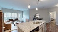 Located at 800 Baldwin Dr. in Grandview Heights, Ohio, this single-floor residence offers a well-designed open-concept layout that seamlessly connects the kitchen, dining, and living areas. Rich hardwood flooring flows throughout the main living space, anchoring a bright and contemporary aesthetic defined by neutral tones and clean lines.

The kitchen is a standout feature, centered around a large granite-topped island with an undermount sink and built-in dishwasher. Pendant lighting illuminates the island, while track lighting adds additional ambiance. Grey shaker-style cabinetry extends to the ceiling, complemented by a white subway tile backsplash and a full suite of stainless steel appliances, including a refrigerator, electric range, and over-the-range microwave.

The living area benefits from generous natural light through large windows, creating an open and inviting atmosphere. A sliding glass door provides access to an outdoor area, further enhancing the sense of space.

The bedroom features plush carpeting, a natural light-filled window, and a walk-in closet with built-in shelving. The bathroom is finished with tile flooring, grey shaker vanity cabinetry, a framed mirror, and a separate shower enclosure. Throughout, the residence balances modern finishes with a warm, comfortable ambiance.