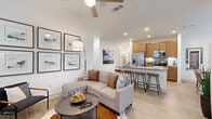 This well-appointed 2-bedroom, 2-bathroom single-story residence in Leander, TX offers a thoughtfully designed open-concept layout that maximizes both function and comfort. Light wood-style flooring flows throughout the main living areas, complemented by crisp white walls and an abundance of natural light from large windows dressed with sheer curtains and blinds.

The kitchen is a standout feature, boasting warm-toned cabinetry, stainless steel appliances including a refrigerator, microwave, and range, and an expansive granite-topped island with bar seating — ideal for casual dining or entertaining. The kitchen opens seamlessly into the living and dining areas, the latter bathed in natural light and offering access to an outdoor space.

The living room is generously proportioned, featuring a ceiling fan and multiple windows that brighten the space. Both bedrooms are carpeted for comfort, each offering ample closet storage. The primary bedroom includes a walk-in closet and a private en-suite bathroom with a granite vanity, tub, and shower. A second full bathroom serves the additional bedroom.

A dedicated laundry room with a full-size washer and dryer adds everyday convenience. The overall ambiance is clean, modern, and welcoming throughout.