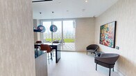 Located at 70 Ordnance Street in Toronto's vibrant King West neighbourhood, this refined single-floor space offers a seamlessly designed open-concept layout that blends contemporary aesthetics with premium finishes throughout.

The living area is a standout, anchored by a generously sized sectional sofa and complementary seating arrangements set against floor-to-ceiling windows that flood the space with natural light. Panoramic views of the Toronto skyline and surrounding cityscape create a dynamic backdrop, enhancing the bright and airy atmosphere. Recessed ceiling lighting and neutral textured wall treatments contribute to the space's calm, sophisticated tone.

The kitchen and social area is equally impressive, showcasing a dramatic black marble island with waterfall edges and bar-height leather seating. A matching marble backsplash and a suite of light wood cabinetry frame the cooking space, while a trio of oversized metallic globe pendant lights serve as a striking focal point overhead. Built-in shelving adds both function and visual interest.

Connecting the zones is a transitional area featuring a wall-mounted media unit with low-profile cabinetry, a mounted flat-screen display, and decorative accents. Light hardwood flooring runs throughout, tying the entire space together with warmth and continuity. The overall design balances urban sophistication with an inviting, functional sensibility.