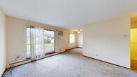 Located in Robbinsdale, MN, this two-story, two-bedroom, two-bathroom home offers a functional and comfortable layout spread across two floors. The main level welcomes you with a carpeted living room featuring a ceiling fan, a sliding glass door that opens to a private balcony with outdoor views, and an additional window that fills the space with natural light. The galley-style kitchen is equipped with warm oak cabinetry, a double sink, a dishwasher, a refrigerator, and durable vinyl plank flooring, with easy access to a dedicated dining area. A staircase with a metal railing connects the main level to the upper floor, where both bedrooms are located. The primary bedroom offers generous proportions with plush carpeting, a closet, and a window with vertical blinds. The second bedroom also features carpet and a window. Two full bathrooms serve the home, including one with mosaic tile flooring, a tiled shower surround, a vanity, and an accessibility grab bar. Throughout the home, baseboard heating provides warmth, and ample storage is available with five closets distributed across both levels. The neutral-toned walls and soft carpeting create a clean, move-in-ready ambiance.