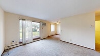 Located in Robbinsdale, MN, this two-story, two-bedroom, two-bathroom home offers a functional and comfortable layout spread across two floors. The main level welcomes you with a carpeted living room featuring a ceiling fan, a sliding glass door that opens to a private balcony with outdoor views, and an additional window that fills the space with natural light. The galley-style kitchen is equipped with warm oak cabinetry, a double sink, a dishwasher, a refrigerator, and durable vinyl plank flooring, with easy access to a dedicated dining area. A staircase with a metal railing connects the main level to the upper floor, where both bedrooms are located. The primary bedroom offers generous proportions with plush carpeting, a closet, and a window with vertical blinds. The second bedroom also features carpet and a window. Two full bathrooms serve the home, including one with mosaic tile flooring, a tiled shower surround, a vanity, and an accessibility grab bar. Throughout the home, baseboard heating provides warmth, and ample storage is available with five closets distributed across both levels. The neutral-toned walls and soft carpeting create a clean, move-in-ready ambiance.