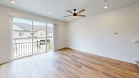 Located in Herriman, Utah, this modern three-story townhome offers a well-organized layout across three distinct levels. The exterior features a classic two-tone facade with neutral siding, a pitched roof, and an attached two-car garage with automatic openers, complemented by low-maintenance xeriscaped landscaping.

The ground floor houses the spacious attached garage, offering ample room for vehicles and storage, with direct interior access to the home. The main living level features an open-concept kitchen and living area with warm-toned luxury vinyl plank flooring that flows throughout the home. The kitchen is equipped with white shaker cabinetry, stainless steel appliances including a gas range and refrigerator, a subway tile backsplash, and recessed lighting. A hallway connects to additional utility spaces on this level.

The upper floor is home to the living room, which features vaulted ceilings, recessed lighting, and dual windows that bring in natural light and neighborhood views. A well-appointed full bathroom includes a soaking tub/shower combo with matte black fixtures, a vanity with neutral countertops, and vinyl plank flooring. The walk-in closet provides built-in shelving and double hanging rods, offering generous storage capacity. Staircases connect all three levels efficiently throughout the home.