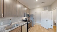 Located at 820 E Long Street in Columbus, Ohio, this two-story residence offers a thoughtfully designed layout spread across two floors. The main level greets visitors with a striking open living area distinguished by dramatic double-height ceilings and tall windows that flood the space with natural light. Light-toned hardwood-style flooring runs throughout, complementing the neutral wall palette and creating a bright, airy ambiance. The kitchen is well-appointed with warm taupe cabinetry, granite countertops, a classic subway tile backsplash, and a full suite of stainless steel appliances, including a range, microwave, dishwasher, and refrigerator. A half bathroom on the main level provides added convenience. The upper floor houses a full bathroom finished with large-format tile flooring, a granite-topped vanity, and a glass-enclosed walk-in shower. A dedicated closet and utility room add practical storage and functionality. Two staircases connect the floors, enhancing circulation throughout the home. Clean architectural lines, recessed lighting, and consistent modern finishes give the entire space a cohesive, contemporary character well-suited for comfortable everyday living.